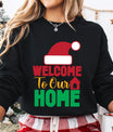 Black sweatshirt with colorful Christmas text “Welcome to Our Home” featuring a red Santa hat and house icon.