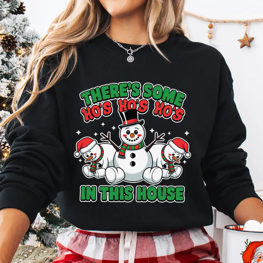 Black sweatshirt featuring three cheerful snowmen and the phrase “There’s Some Ho’s In This House” in red and green Christmas colors.