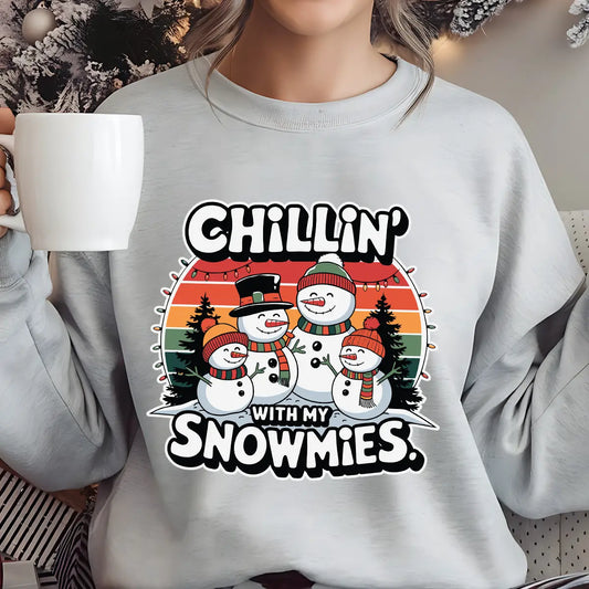Gray sweatshirt with a retro sunset background featuring three cheerful snowmen and the text “Chillin’ With My Snowmies.”