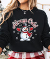 Black sweatshirt with smiling snowman wearing a top hat and red scarf with text “Always Cold.”