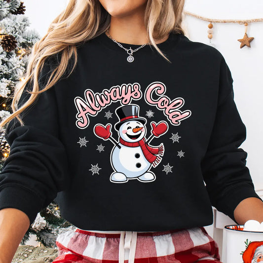 Black sweatshirt with smiling snowman wearing a top hat and red scarf with text “Always Cold.”
