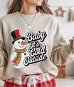 Beige sweatshirt featuring a smiling snowman with a top hat and striped scarf alongside the phrase “Baby It’s Cold Outside,” perfect for cozy winter or Christmas apparel.