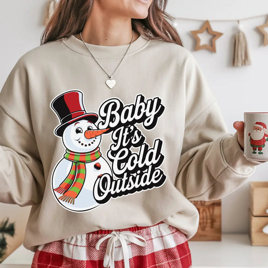 Beige sweatshirt featuring a smiling snowman with a top hat and striped scarf alongside the phrase “Baby It’s Cold Outside,” perfect for cozy winter or Christmas apparel.
