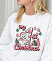 White sweatshirt featuring a pink and green “My 1st Christmas” DTF transfer design with a snowman, candy cane, ornaments, and presents—perfect for baby’s first holiday.