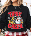 Black sweatshirt with cheerful snowman holding a wine glass and bold red and yellow text “Tipsy & Full of Cheer,” perfect for fun Christmas party apparel.