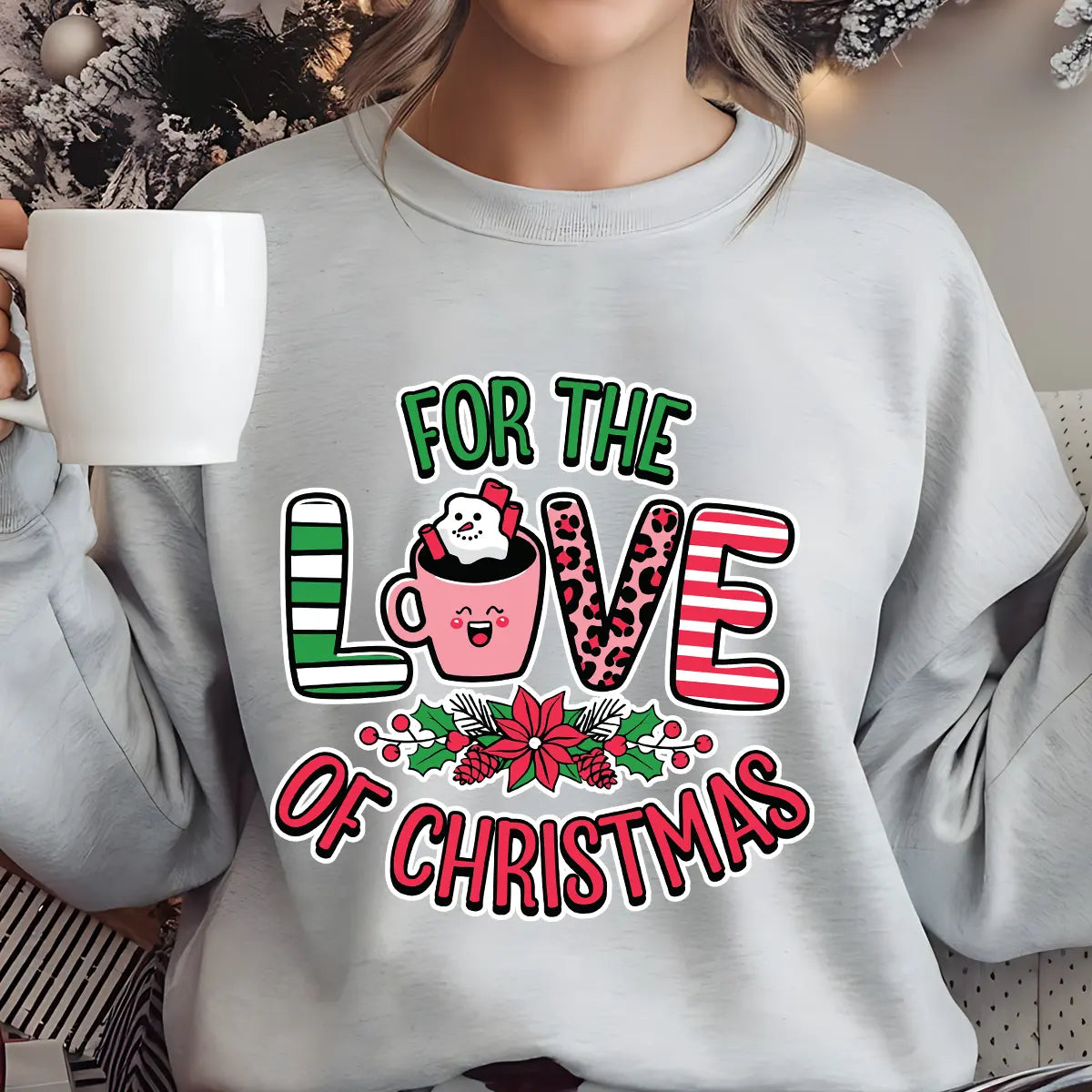 Gray sweatshirt featuring a pink hot cocoa mug with marshmallows and candy cane, surrounded by holly and the text “For the Love of Christmas” in festive red and green.