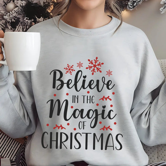 Gray sweatshirt featuring the phrase “Believe in the Magic of Christmas” in elegant black script with red snowflakes and accents—perfect for festive holiday apparel.