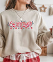 Beige sweatshirt featuring a red and white “Christmas” DTF transfer design with Santa hats, stockings, snowflakes, and ornaments—festive and cheerful holiday style.