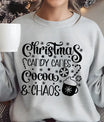 Gray sweatshirt featuring the phrase “Christmas Candy Canes Cocoa & Chaos” in fun black script with stars, candy canes, and a cocoa mug—playful holiday design.
