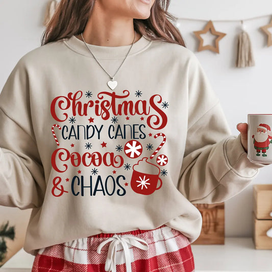 Beige sweatshirt featuring the phrase “Christmas Candy Canes Cocoa & Chaos” in red and navy lettering with candy canes, cocoa mug, and snowflakes—festive holiday design.