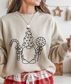 Sand-colored sweatshirt featuring black line-art DTF design of a Christmas gnome holding a candy cane and peppermint lollipop.