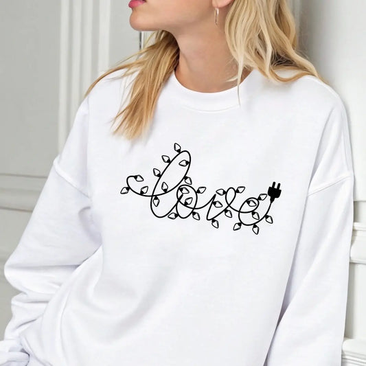White sweatshirt with DTF design spelling “love” in Christmas light string style, minimalist holiday graphic.