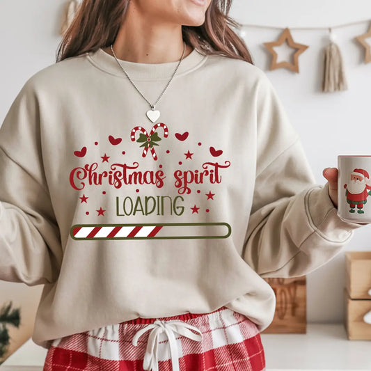 Sand-colored sweatshirt with “Christmas Spirit Loading” DTF design featuring red hearts, candy cane bow, and festive progress bar.