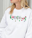 White sweatshirt with colorful “Christmas” DTF design featuring ornaments, stars, antlers, and Santa hat accents.