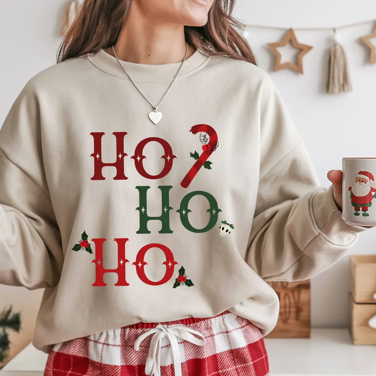 Beige sweatshirt with “Ho Ho Ho” red and green Gothic Christmas DTF design, featuring candy cane, holly leaves, and small skull accents.