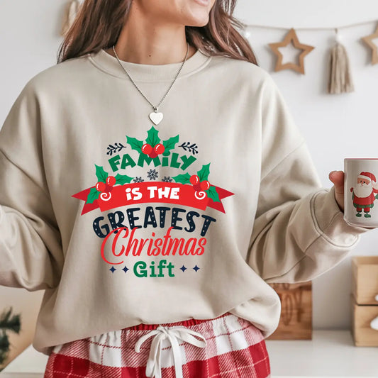 Sand-colored sweatshirt with “Family Is the Greatest Christmas Gift” festive DTF design in red, green, and navy with holly leaf accents.
