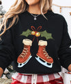 Black sweatshirt with Christmas DTF design showing brown ice skates, holly leaves, golden bells, and a red bow.