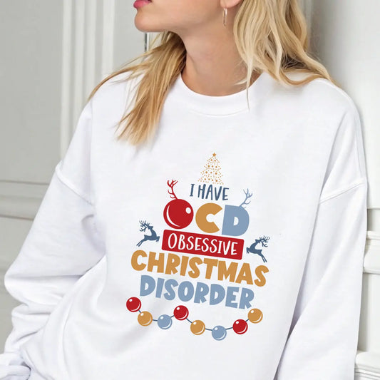 White sweatshirt featuring colorful “I Have OCD – Obsessive Christmas Disorder” design with reindeer, ornaments, and Christmas tree.