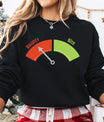 Black sweatshirt with a colorful red and green “Naughty or Nice” meter DTF transfer design, arrow pointing toward “Naughty.”