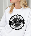 White sweatshirt featuring a black and white circular “Official Santa Seal of the North Pole” DTF transfer design.