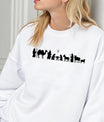 White sweatshirt with minimalist black nativity scene silhouette DTF transfer showing Mary, Joseph, baby Jesus, shepherds, and animals.