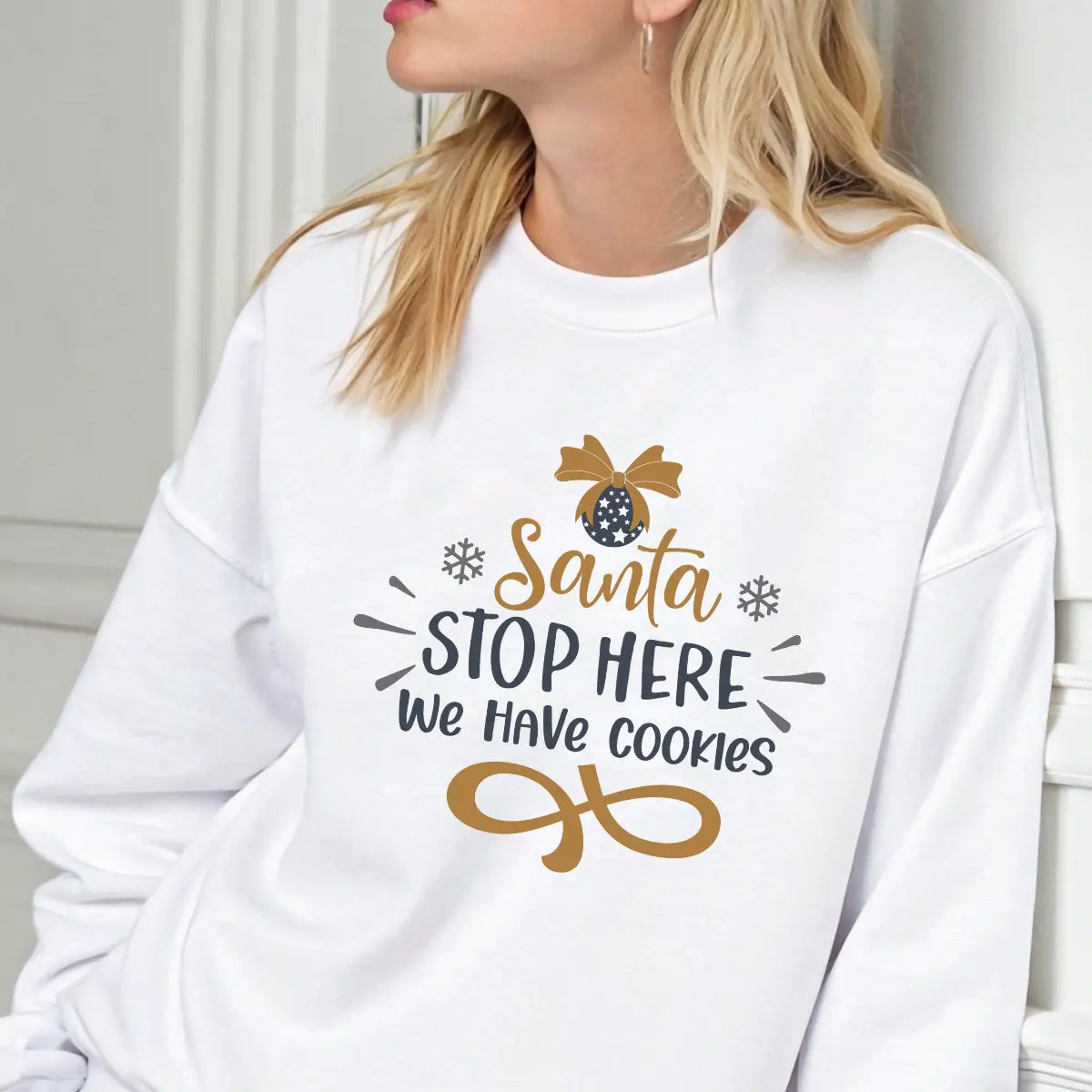 White sweatshirt with “Santa Stop Here We Have Cookies” DTF design in gold and black featuring an ornament and snowflakes.