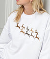 White sweatshirt with gold, bronze, and taupe reindeer silhouettes in flight, elegant gradient DTF transfer design for Christmas apparel.