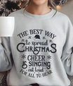 Grey sweatshirt with “The Best Way to Spread Christmas Cheer is Singing Out Loud for All to Hear” text design and Santa hat accent – festive holiday DTF print.