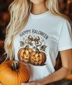 White t-shirt with two smiling jack-o’-lanterns tied with a bow and “Happy Halloween” text in vintage style, perfect for fall and Halloween outfits.