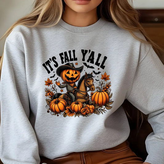 Gray sweatshirt with pumpkin-headed cowboy riding a horse surrounded by pumpkins and fall leaves—It’s Fall Y’all DTF transfer design.