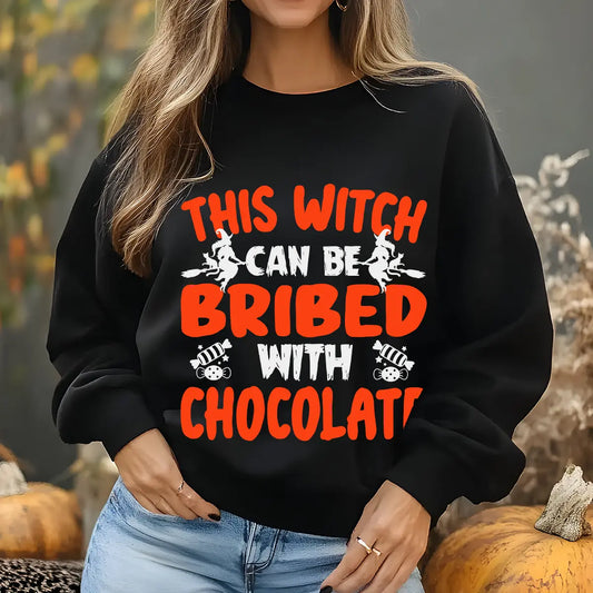 Black sweatshirt with bold orange and white text “This Witch Can Be Bribed with Chocolate” DTF transfer design featuring flying witches and candy graphics.