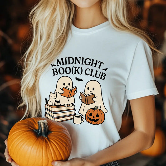 White t-shirt featuring two cute ghosts reading books with a cat, pumpkin, and coffee mug under text “Midnight Boo(k) Club.”