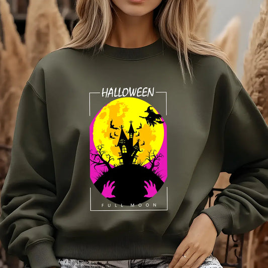Green sweatshirt featuring a haunted house, witch, bats, and full moon Halloween DTF transfer design with bright yellow and pink tones.