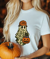 White t-shirt featuring a ghost in camouflage with an orange “Candy Hunter” hat and pumpkin candy bucket Halloween DTF transfer design.