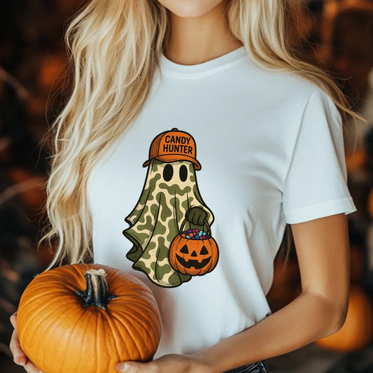 White t-shirt featuring a ghost in camouflage with an orange “Candy Hunter” hat and pumpkin candy bucket Halloween DTF transfer design.