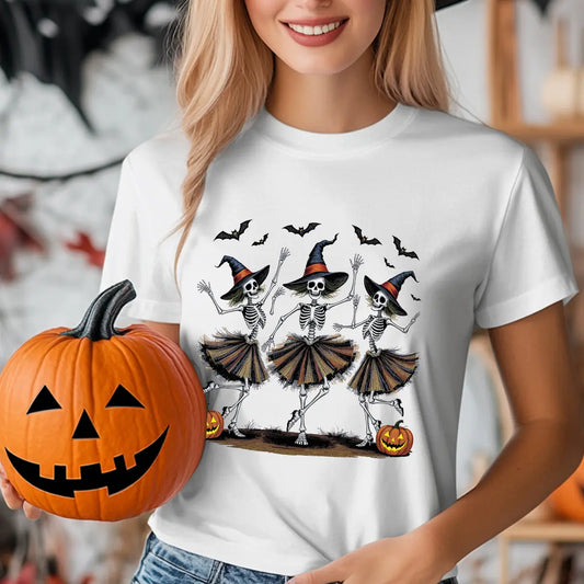 White T-shirt with three dancing skeleton witches wearing hats and skirts, surrounded by bats and pumpkins, Halloween DTF transfer design.