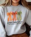 Gray sweatshirt with three fall-colored bows and text “Grateful Thankful Blessed – God is faithful in every season.”