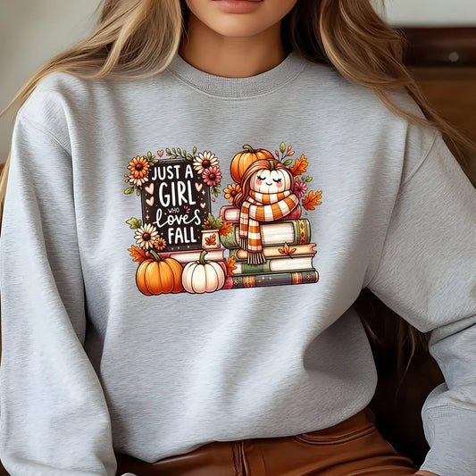 Grey sweatshirt with a fall-themed DTF design featuring a cute pumpkin character, books, flowers, and the text “Just a Girl Who Loves Fall.”