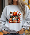 Grey sweatshirt with fall-themed DTF design featuring pumpkins, books, flowers, and a scarf, with the text “Just a Girl Who Loves Fall.”