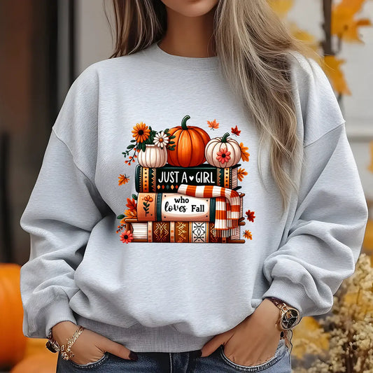 Grey sweatshirt with fall-themed DTF design featuring pumpkins, books, flowers, and a scarf, with the text “Just a Girl Who Loves Fall.”