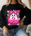 Black sweatshirt featuring a cute ghost holding a pink ribbon, surrounded by daisies and bows in a pink checkered frame for breast cancer awareness.