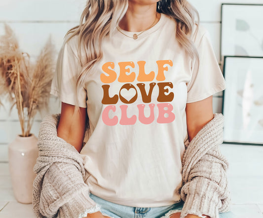 Self Love Club DTF Transfer design with retro typography in warm colors on a cream T-shirt worn by a woman.