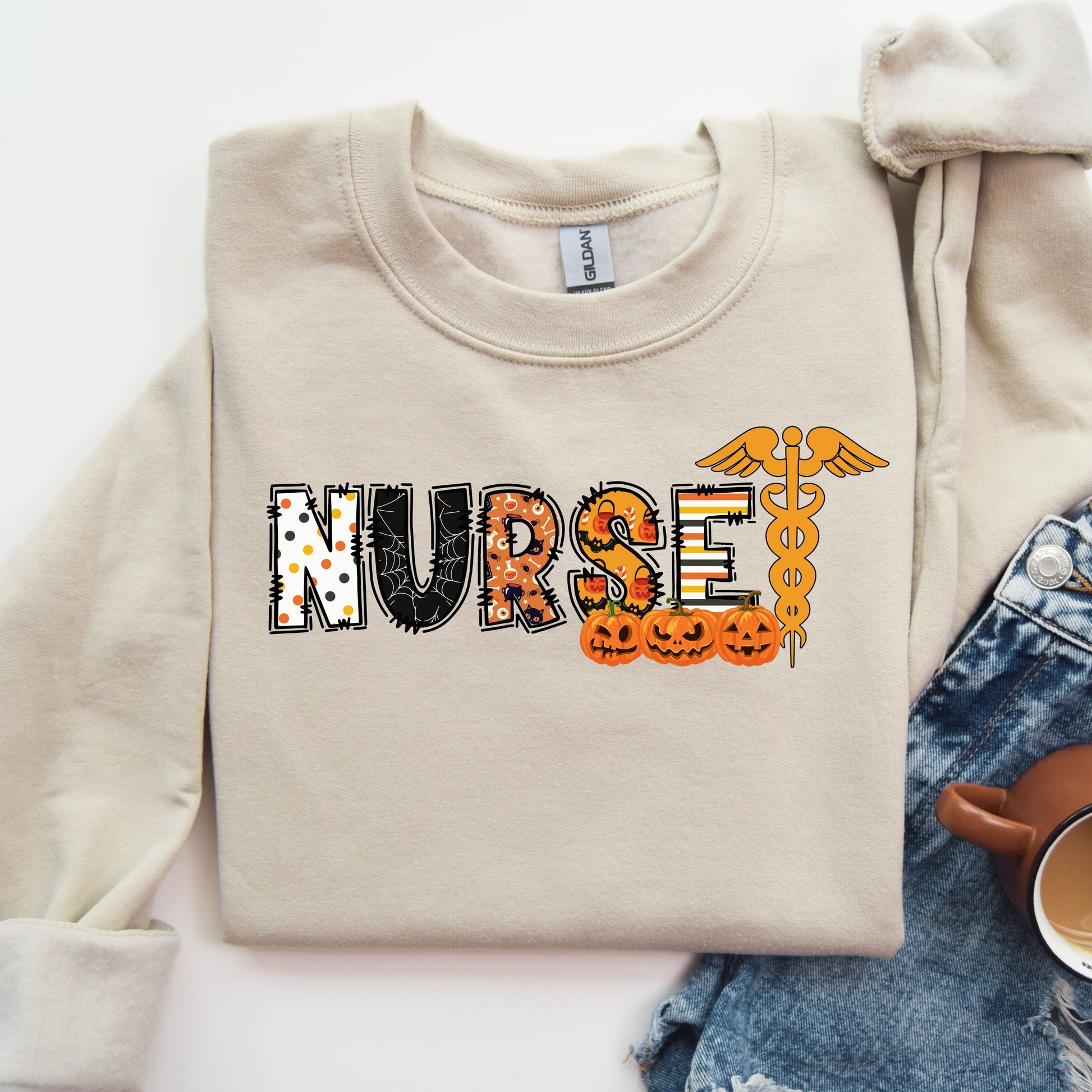 Halloween-themed nurse DTF transfer design with pumpkins, cobwebs, and caduceus symbol on a beige shirt.