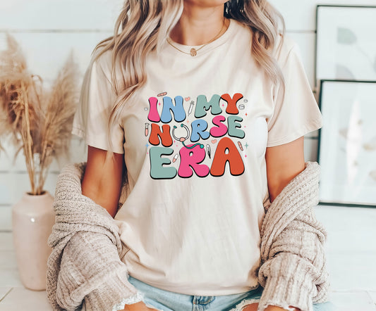 "In My Nurse Era" DTF Transfer on a beige t-shirt with colorful text and medical illustrations.